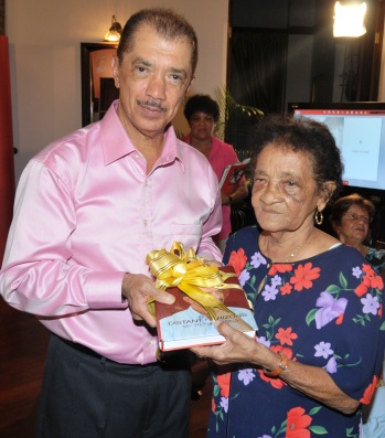 Mr Michel presents the first copy of the book to his mother during the launch ceremony yesterday evening