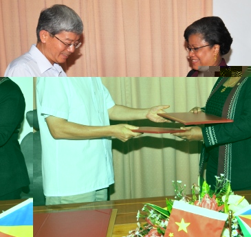 Mr Wang and Dr Athanasius exchange documents after the signing