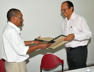 Dr Payet and Mr Racombo exchange documents after the signing