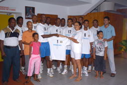 Mrs Gonzalez hands over a replica of the T-Shirt to Racing Club’s captain Tony Songor in the presence of other team members
