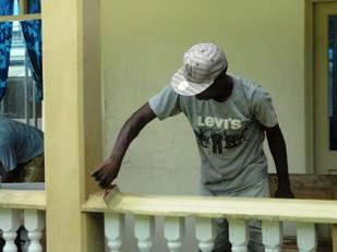 A member of the Les Mamelles team giving a fresh coat of paint to one of the hospital’s room verandas